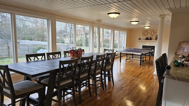 dining space featuring ornamental molding, wood ceiling, a fireplace, and wood finished floors