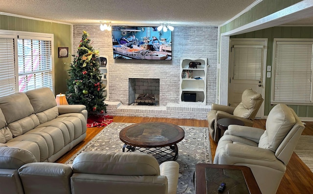 living area featuring a textured ceiling, ornamental molding, a fireplace, and wood finished floors