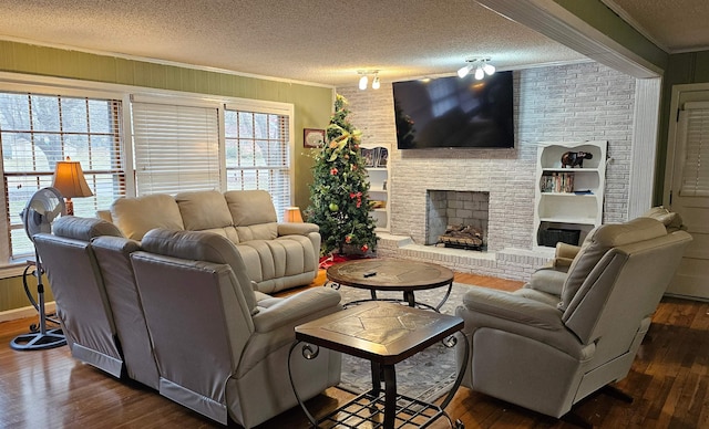 living area featuring ornamental molding, a fireplace, a textured ceiling, and wood finished floors