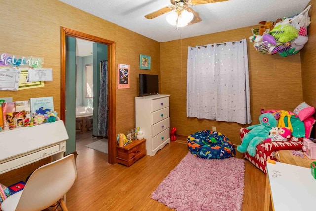bedroom featuring a ceiling fan, ensuite bath, and wood finished floors