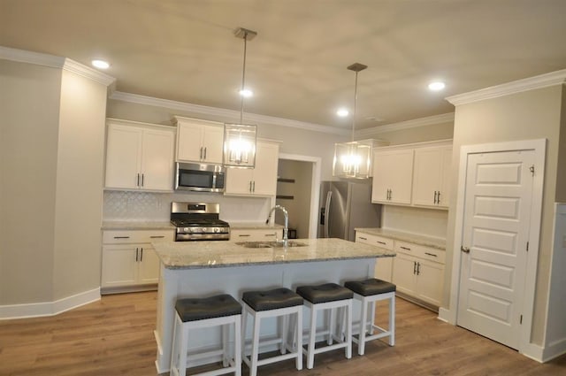  - kitchen featuring stainless steel appliances, a sink, white cabinets, tasteful backsplash, and crown molding