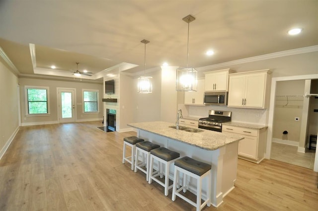  - kitchen with appliances with stainless steel finishes, ornamental molding, a sink, open floor plan, and white cabinetry