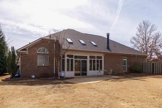 back of property with a shingled roof, a sunroom, fence, a patio area, and brick siding