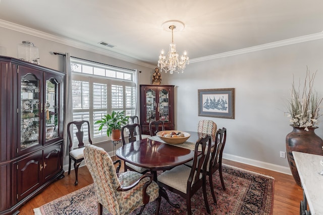 dining area with crown molding, visible vents, an inviting chandelier, wood finished floors, and baseboards