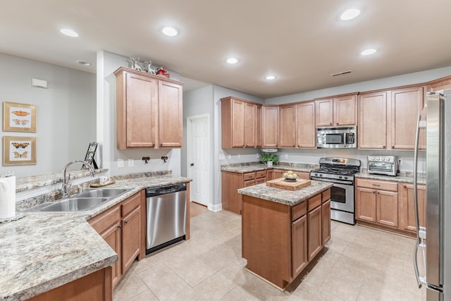 kitchen featuring visible vents, a kitchen island, a peninsula, stainless steel appliances, and a sink