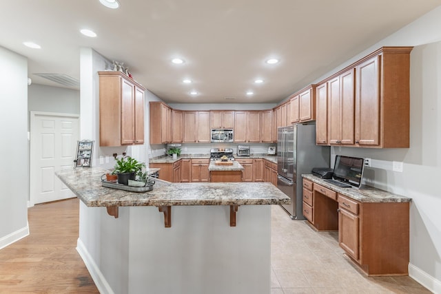 kitchen featuring appliances with stainless steel finishes, a breakfast bar, and brown cabinetry