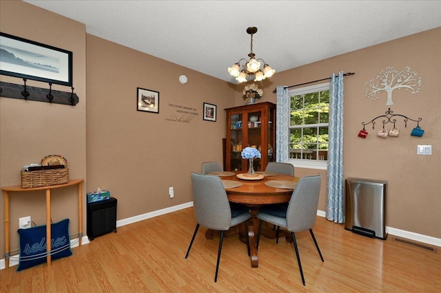  - dining area featuring a chandelier and light wood-style floors