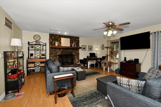  - living area with wood finished floors, ceiling fan, a textured ceiling, a fireplace, and an office area