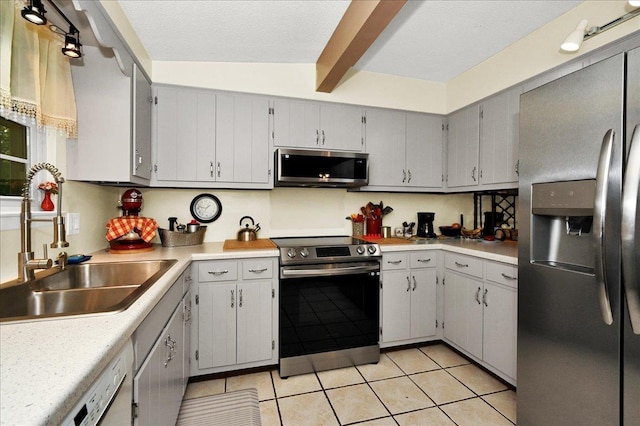  - kitchen with stainless steel appliances, beam ceiling, light tile patterned floors, and light countertops
