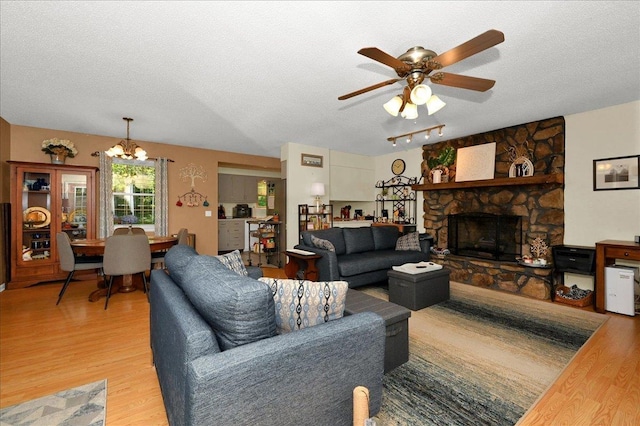 - living room with a textured ceiling, light wood-style floors, a chandelier, a ceiling fan, and a fireplace