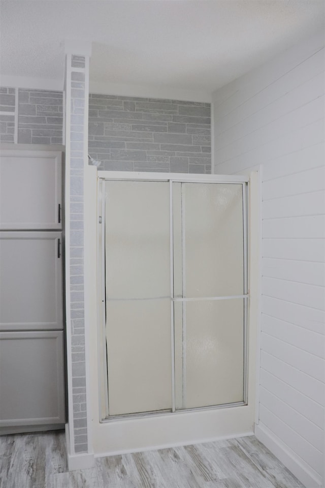  - bathroom featuring baseboards, wood finished floors, and a shower stall