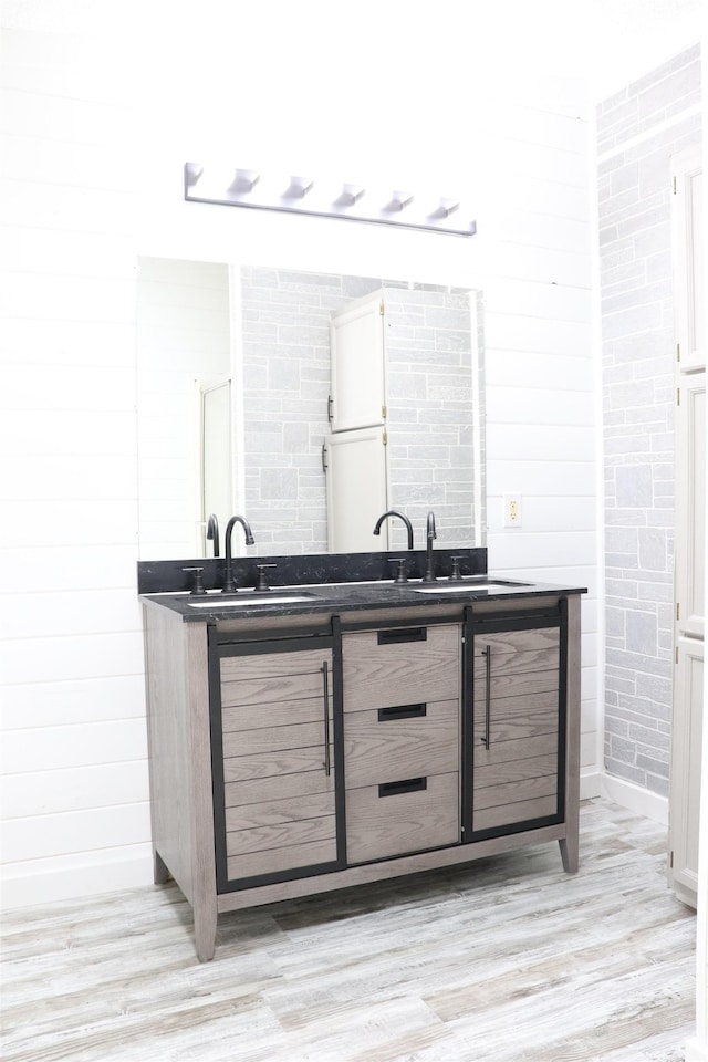  - bar with a sink, baseboards, and light wood-type flooring