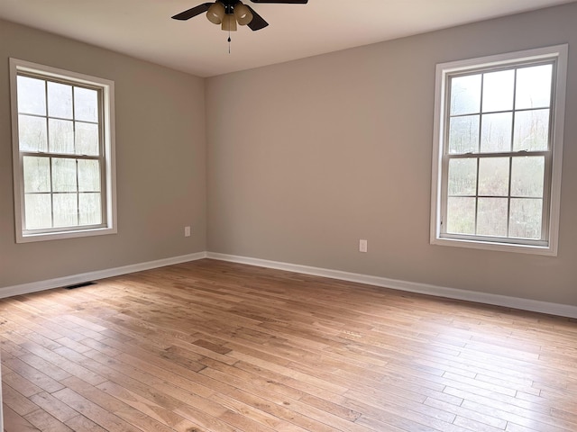 spare room with light wood-type flooring, ceiling fan, and a healthy amount of sunlight