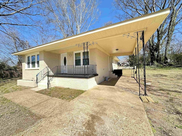 view of front facade featuring an attached carport, concrete driveway, covered porch, and brick siding