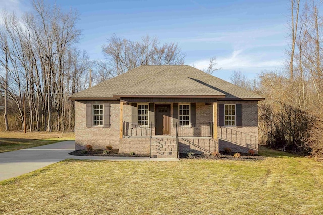 view of front of home with brick siding, covered porch, a front yard, and a shingled roof