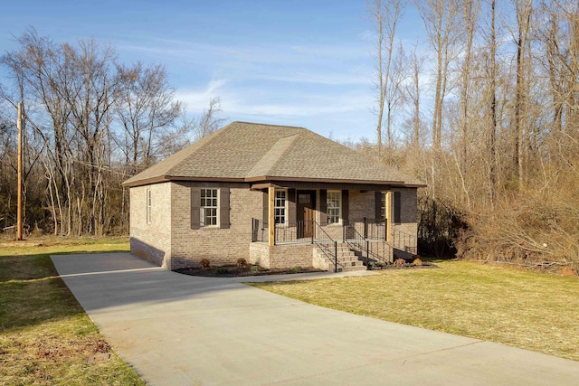 view of front of property featuring a front yard, roof with shingles, a porch, concrete driveway, and brick siding