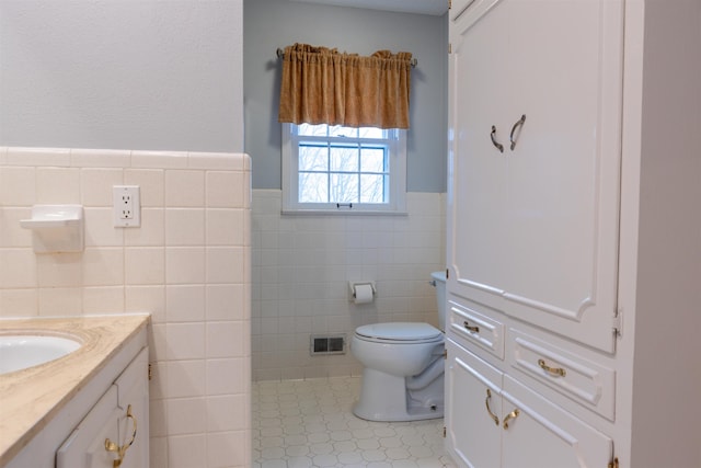 bathroom featuring vanity, tile patterned flooring, tile walls, and toilet