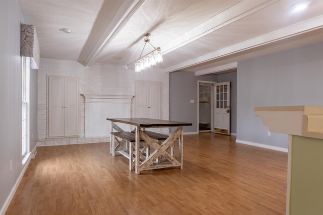 dining area featuring beam ceiling, brick wall, and hardwood / wood-style flooring