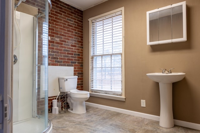 bathroom featuring brick wall, toilet, and a shower with shower door