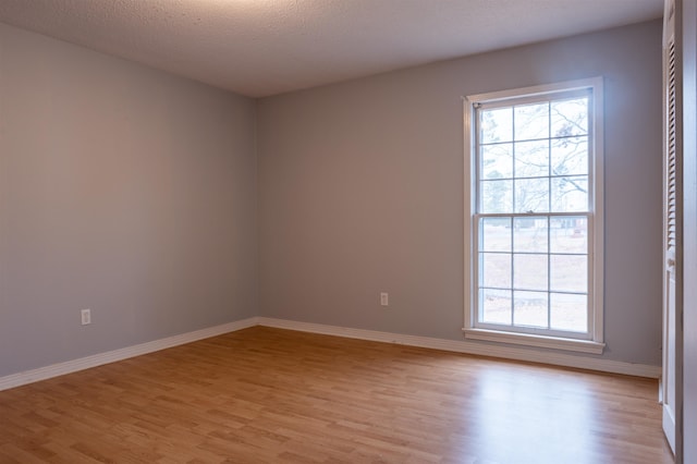 spare room with a textured ceiling and light wood-type flooring