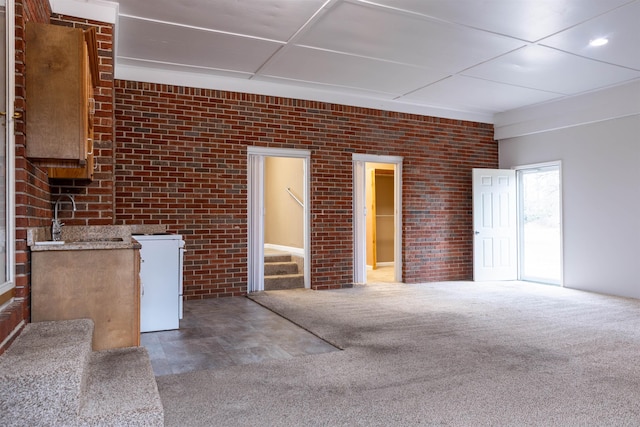 interior space with brick wall, sink, and carpet