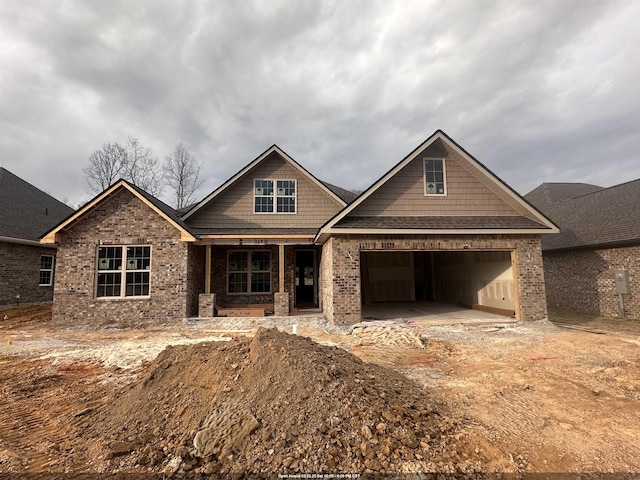 craftsman inspired home with a garage, covered porch, and brick siding