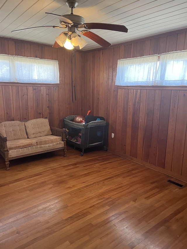 unfurnished room featuring a ceiling fan, visible vents, wood-type flooring, and wood walls