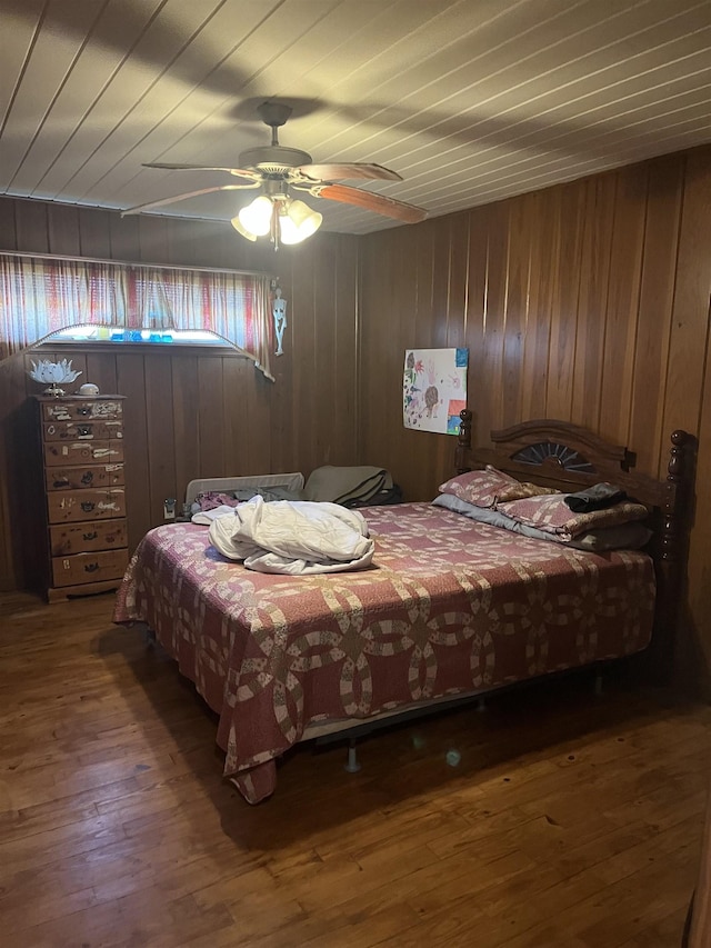 bedroom with wooden ceiling, wooden walls, wood finished floors, and a ceiling fan