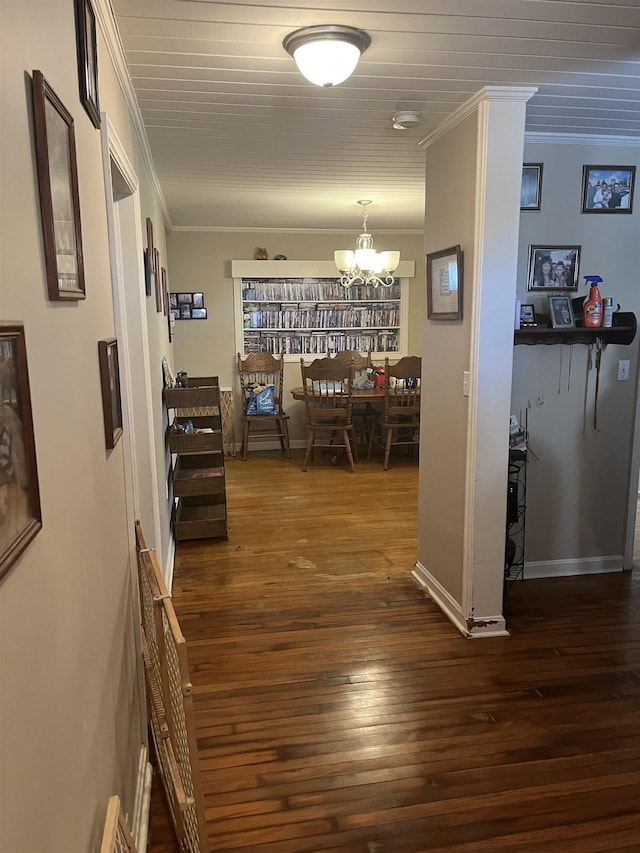 hall with a notable chandelier, baseboards, crown molding, and dark wood-type flooring