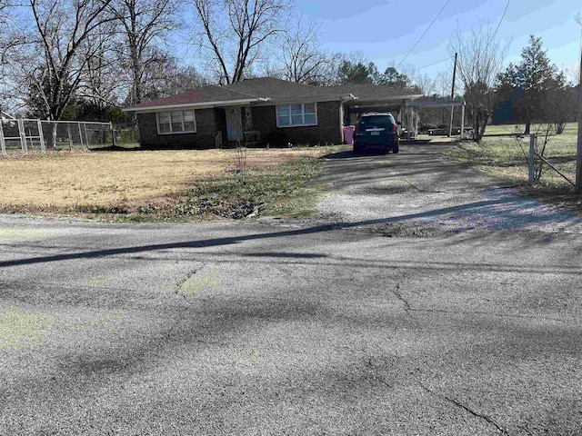 view of front of property featuring aphalt driveway, brick siding, and fence