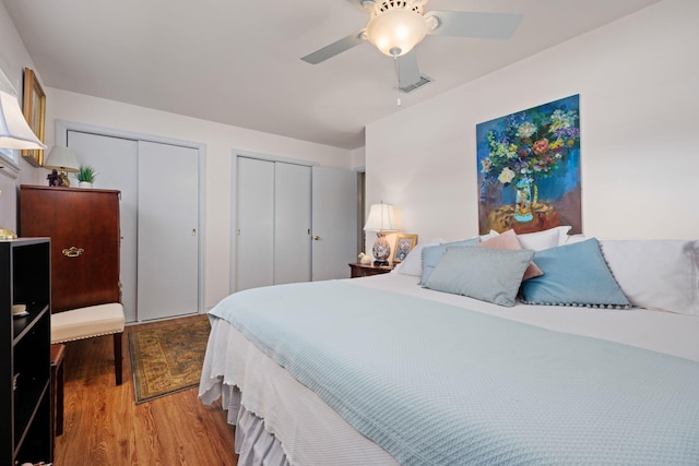 bedroom featuring multiple closets, ceiling fan, and wood-type flooring