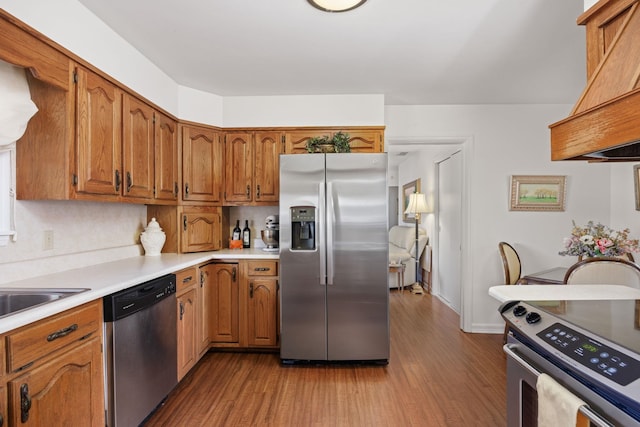 kitchen featuring decorative backsplash, appliances with stainless steel finishes, and hardwood / wood-style flooring