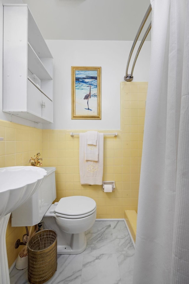 bathroom featuring toilet, curtained shower, and tile walls