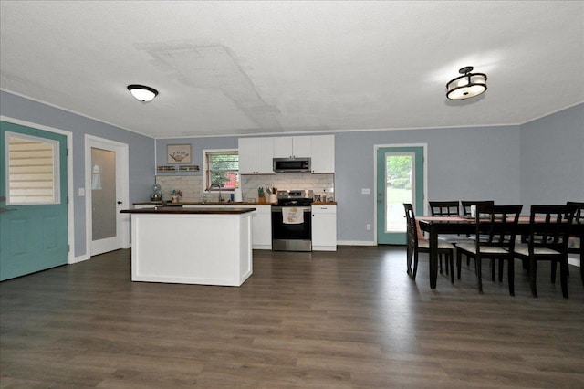  - kitchen with appliances with stainless steel finishes, dark wood-style flooring, white cabinets, and plenty of natural light