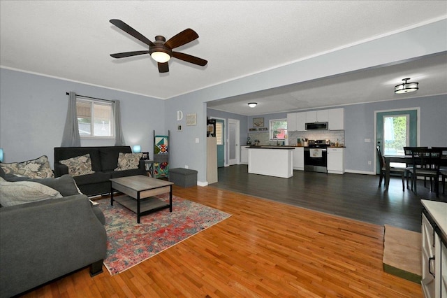  - living area with a ceiling fan, wood finished floors, baseboards, and crown molding