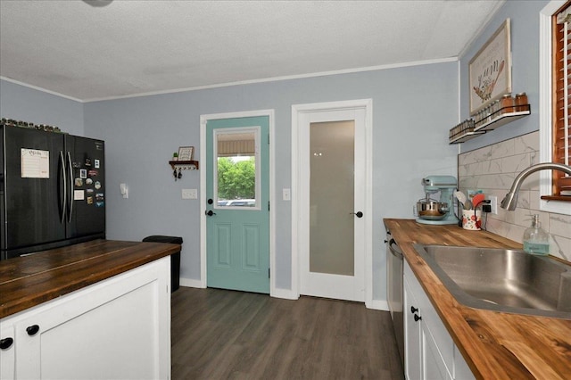  - kitchen featuring butcher block counters, freestanding refrigerator, a sink, crown molding, and dark wood-type flooring