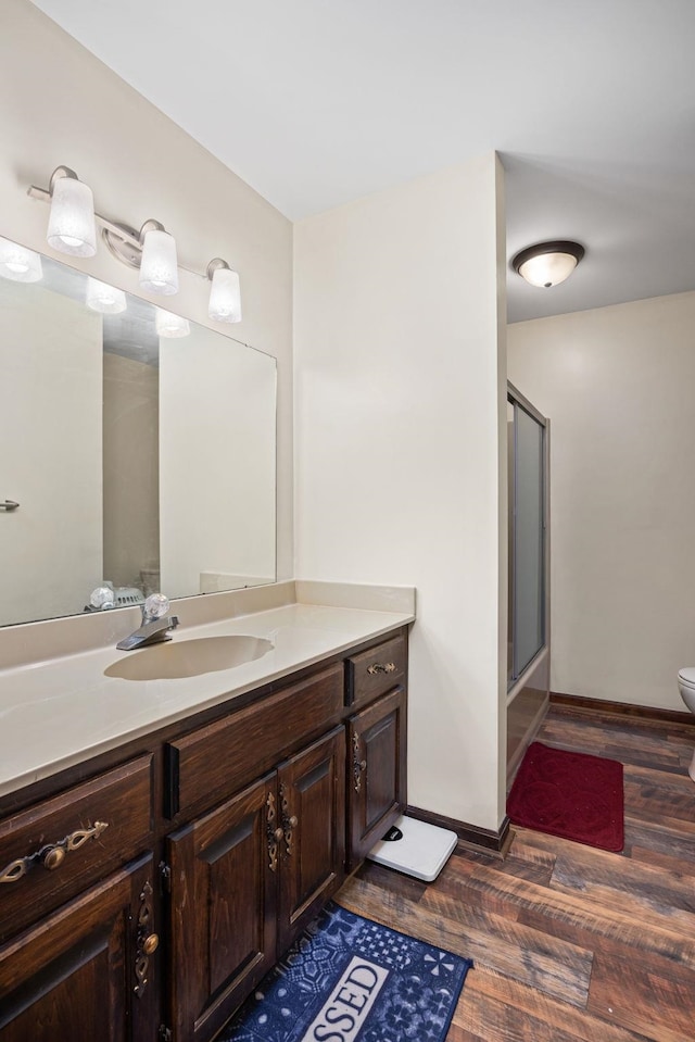 full bathroom with hardwood / wood-style flooring, vanity, toilet, and bath / shower combo with glass door