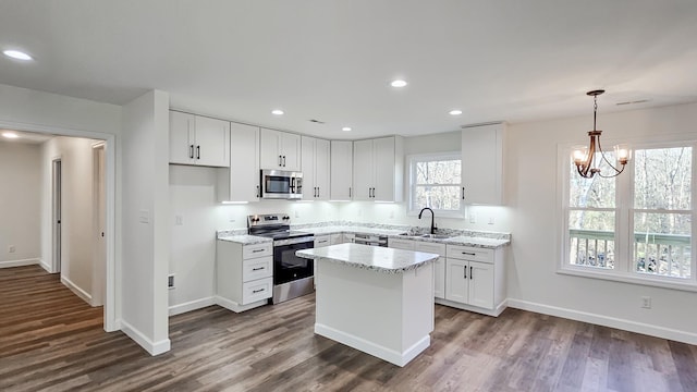 kitchen with sink, white cabinetry, light stone counters, a center island, and stainless steel appliances