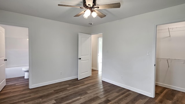 unfurnished bedroom featuring ceiling fan, connected bathroom, dark hardwood / wood-style flooring, a spacious closet, and a closet