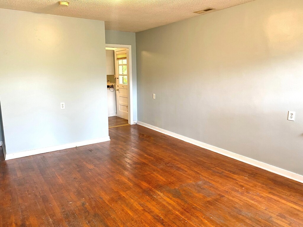  - unfurnished room featuring hardwood / wood-style floors, baseboards, and a textured ceiling