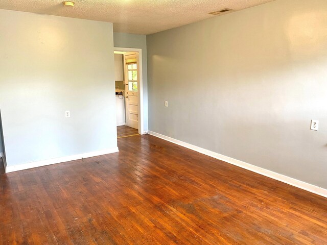  - unfurnished room featuring hardwood / wood-style floors, baseboards, and a textured ceiling