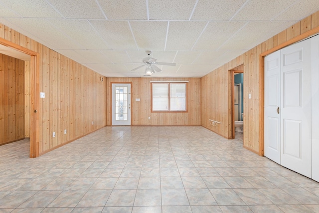 tiled spare room with ceiling fan and wooden walls