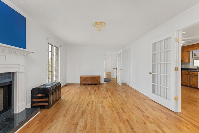 living room featuring french doors, crown molding, light hardwood / wood-style flooring, and a textured ceiling