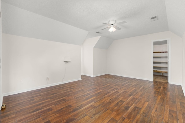 bonus room featuring vaulted ceiling, dark wood-type flooring, a textured ceiling, and ceiling fan