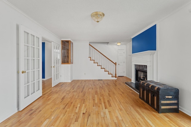 living room featuring french doors, ornamental molding, hardwood / wood-style floors, and a textured ceiling