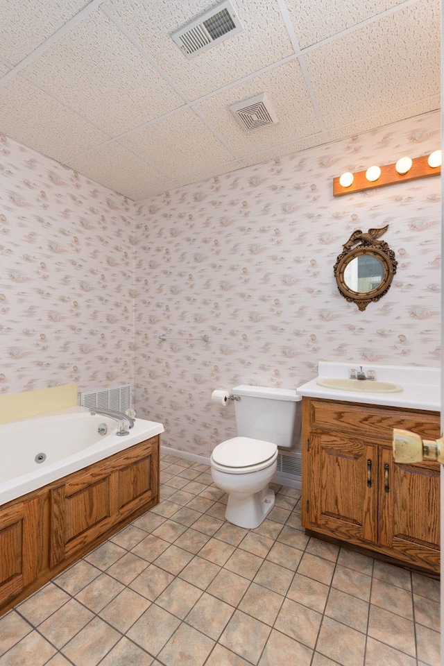 bathroom with a bathing tub, a paneled ceiling, tile patterned flooring, vanity, and toilet