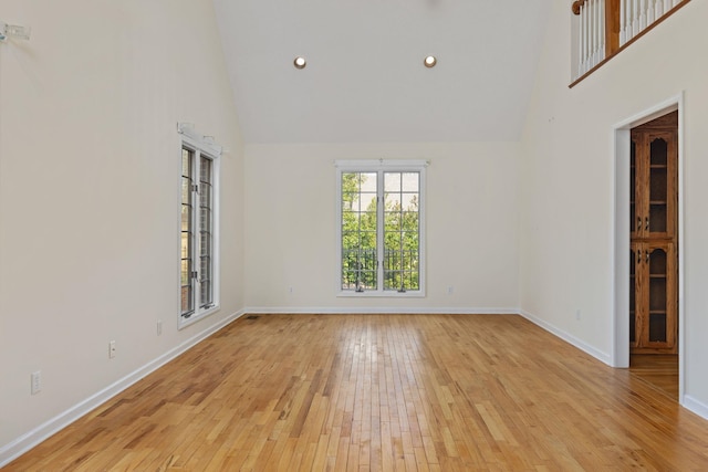 spare room with a towering ceiling and light hardwood / wood-style flooring