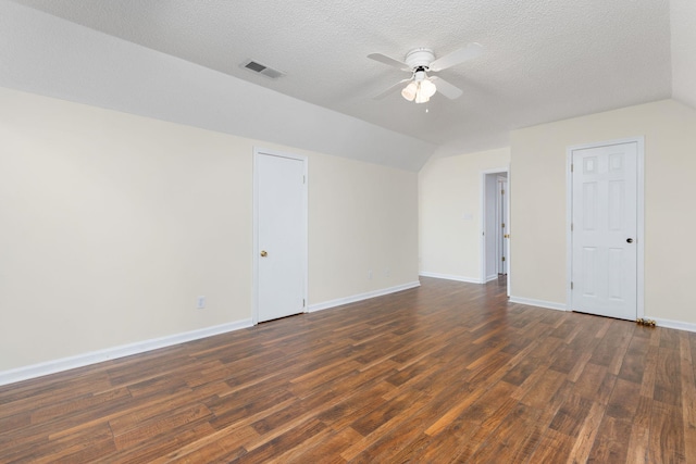 empty room with lofted ceiling, dark hardwood / wood-style floors, a textured ceiling, and ceiling fan