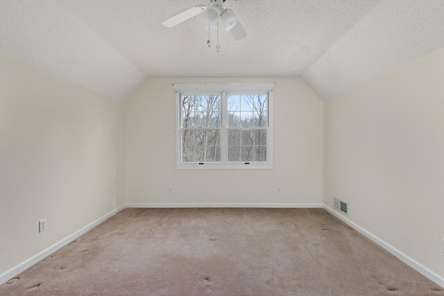 additional living space featuring light carpet, ceiling fan, vaulted ceiling, and a textured ceiling