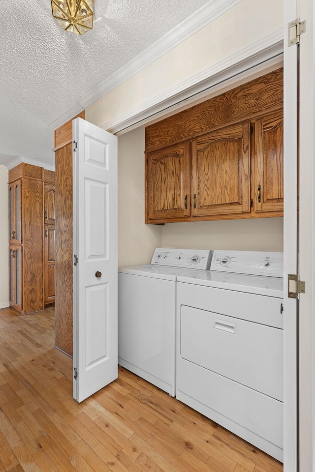 washroom with crown molding, cabinets, washer and clothes dryer, and light hardwood / wood-style floors